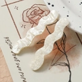 Nahaufnahme gewellter Haarklammern aus perlmuttweißem Acryl mit glänzender Textur - Milchweiß