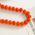 Close-up of bright orange pumpkin-shaped glass beads for jewelry making - Red