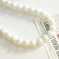 Close-up of ribbed pumpkin-shaped white glass beads arranged in a curve for DIY jewelry - White