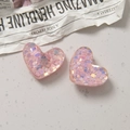 Close-up of translucent pink heart resin charms with holographic glitter for DIY crafts - Pink