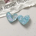 Macro shot of two heart-shaped light blue resin charms with sparkling glitter flakes - Light Blue