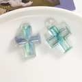 Detalle de colgantes de cruz de resina jaspeada azul verde con agujeros en un plato blanco - Verde Lago Transparente