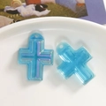 Detalle macro del colgante de cruz de resina azul translúcida con purpurina fina y agujero - Azul