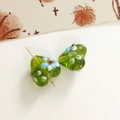 Macro detail of heart-shaped green glass beads with floral patterns and a metal pin - 1 Piece / Green