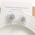 Boucles d'oreilles fleurs en perles de cristal bleu sur une assiette en porcelaine texturée - Fleurs Perlées à la Main / Bleu