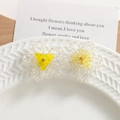 Gros plan de boucles d'oreilles fleurs en perles de cristal sur un plateau en céramique - Fleurs Perlées à la Main / Jaune