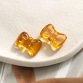 Detailed view of two amber translucent glitter resin bow accessories on a display plate - Amber