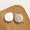 Dettaglio macro di ciondoli in madreperla naturale con perni dorati su base in legno - Bianco