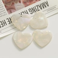 Macro view of iridescent aurora glitter heart charms for DIY jewelry and acrylic crafts - White