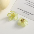 Makroaufnahme hellgrüner Orchideen-Ohrringe aus Harz auf einer minimalistischen Karte - Grün