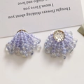 Macro view of purple beaded fan earrings with iridescent crystal droplets and gold base - Purple