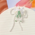 Detailed view of iridescent beaded bow earrings with orchid charms on a white tray - Butterfly Knot Tassel Style