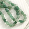 Gros plan de perles ovales en aventurine verte naturelle sur une assiette en porcelaine - Style Aventurine (0802)
