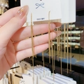 Long golden tassel earrings with S925 silver needles on a white jewelry card - Gold