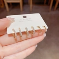 Vue macro détaillée de trois paires de boucles d'oreilles dorées avec zircons sur carte - Style Rond Entièrement en Zircone Doré