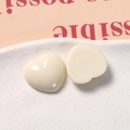 Detail of cream-colored resin heart charms for DIY jewelry making on a white ceramic plate - Creamy White