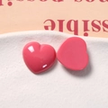 Macro view of two peach pink heart resin charms for DIY craft jewelry on a tray - Rose Red