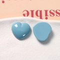 Close-up of blue resin heart charms for DIY jewelry and hair accessories on a white tray - Blue