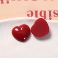 Close-up of bright red resin heart charms with a glossy finish on a white tray - Burgundy