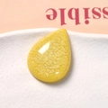 Dettaglio macro di ciondolo in resina gialla a goccia con trama a crepe e finitura lucida - Giallo