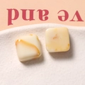 Primer plano de dijes cuadrados de resina crema con textura marmoleada ámbar para joyería - Color Té con Leche