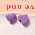 Macro detail of glossy purple resin heart charms on a white ceramic plate for DIY jewelry - Purple