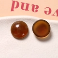 Primo piano di cabochon in resina ambrata da 18mm con motivi a inchiostro su piatto bianco - Rotondo Ambra