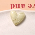 Vue macro d'un cabochon en forme de cœur en résine crème avec texture marbrée DIY - Blanc Cassé