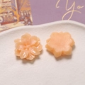 Detailed peach resin gardenia flower charms displayed on a textured white ceramic tray - Orange