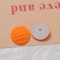 Makroaufnahme matter runder Accessoires mit orangefarbenem Karomuster und Loch auf Rückseite - Orange