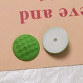 Makro-Detail grüner Silikonkappen mit Karomuster-Textur und weißem Befestigungsloch hinten - Grün