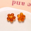 Macro shot of amber orange resin flower pendants for DIY jewelry and hair accessories - Orange