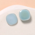 Dettaglio macro di orecchini a perno in resina azzurra su vassoio di ceramica bianca - Azzurro