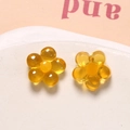 Macro shot of two yellow resin flower charms with five petals for DIY jewelry crafts - Yellow
