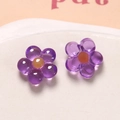 Macro detail of purple resin flower charms with orange centers on a white tray - Purple