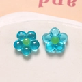 Macro view of blue translucent resin flower charms with green center for DIY jewelry making - Blue