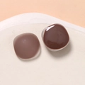 Close-up of matte and glossy brown resin square charms on a white ceramic tray - Coffee