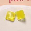 Macro shot of yellow square resin pendants with marble texture on white ceramic plate - Glossy Water Ripple Style / Yellow