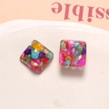 Macro shot of square resin earrings with colorful mosaic stone inlays and clear finish - Square Style