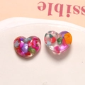 Close-up of heart-shaped transparent resin charms filled with colorful shell sequins - Heart Style