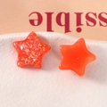 Dettaglio di stelle in resina arancione traslucida con glitter e superfici lisce - Rosso