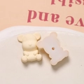 Macro-opname van matte crème berenbedeltjes van hars met centraal rijggat voor DIY-sieraden - Beige