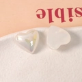 Detalle macro de dijes de resina en forma de corazón con acabado irisado y blanco - Blanco