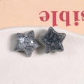 Dettaglio di due ciondoli a stella in resina grigio scuro glitterata per gioielli fai da te - Grigio Argento