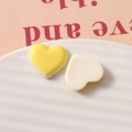 Macro shot of yellow and cream resin heart charms in a textured white ceramic plate - Yellow