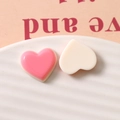 Detailed macro view of pink and creamy white heart resin DIY charms on a white textured tray - Rose Red