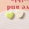 Close-up of heart-shaped resin cabochons in pastel green and white for DIY crafts - Green