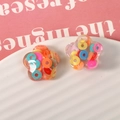Detailed macro shot of transparent flower-shaped resin beads with colorful clay confetti - Colorful