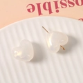 Dettaglio macro di perline in resina a forma di cuore con finitura perlata e perni dorati - Bianco