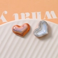 Macro detail of glossy heart-shaped pearl charms with iridescent finish for DIY crafts - Orange